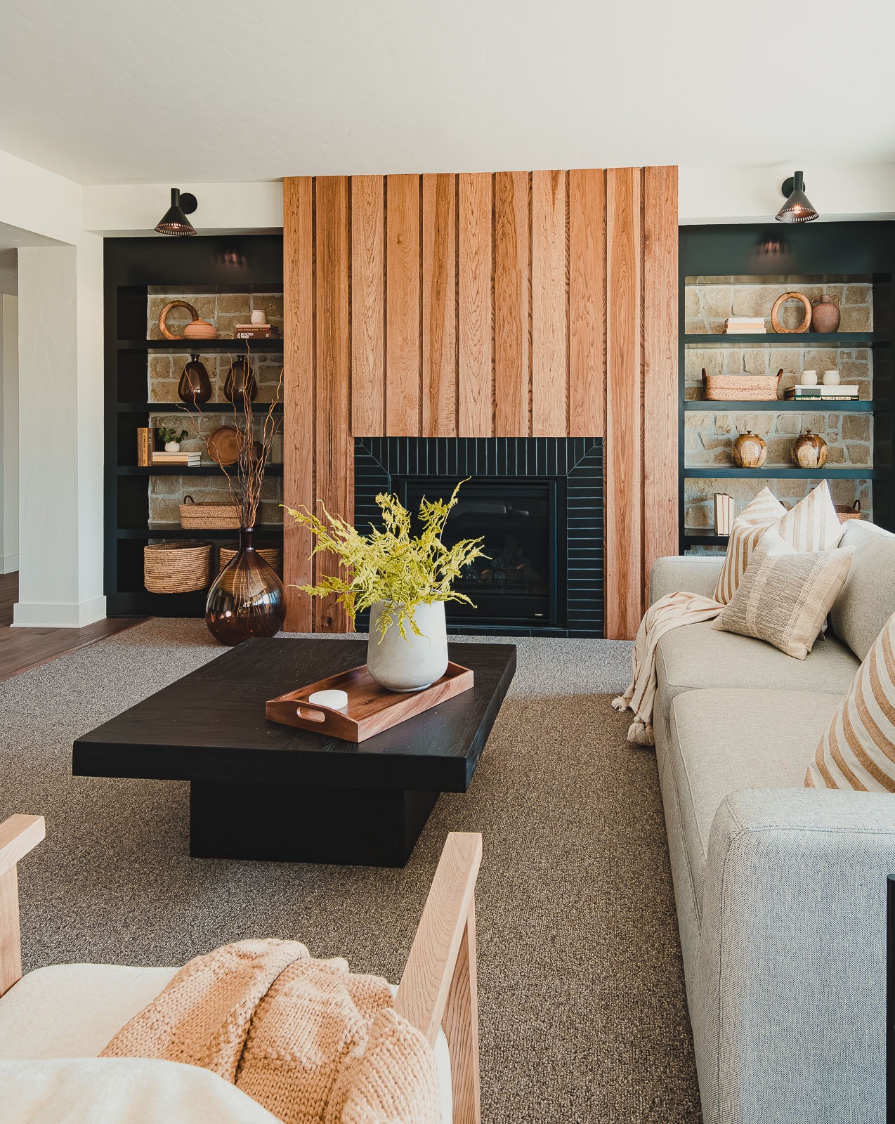 This lower-level family room features black built-in cabinets framing a fireplace in this warm, inviting model home designed for the Fall 2023 Model Home Tour in North Kansas City, Missouri by Sara Svehla Interior Design. Learn more about our home builder services online.