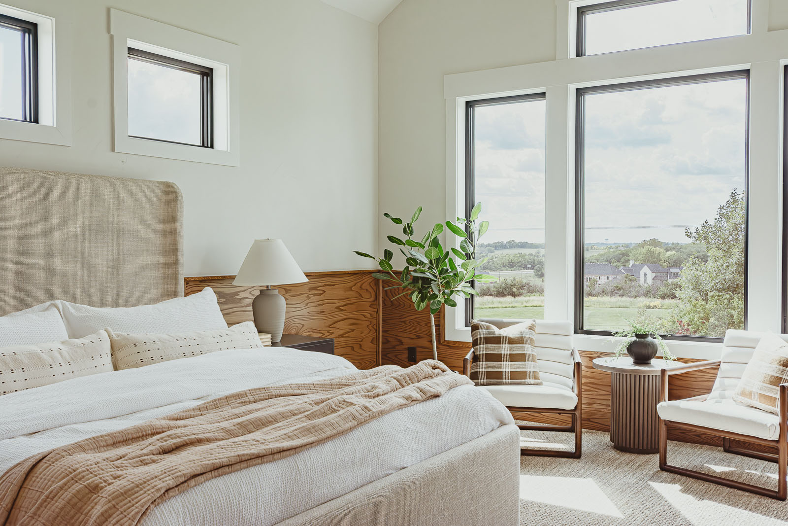 this warm inviting primary bedroom with wood paneled wainscoting overlooks a golf course in north Kansas City. It was part of the 2023 Fall Model Home Tour and was designed by Sara Svehla Interior Design. Warm Inviting Model Home