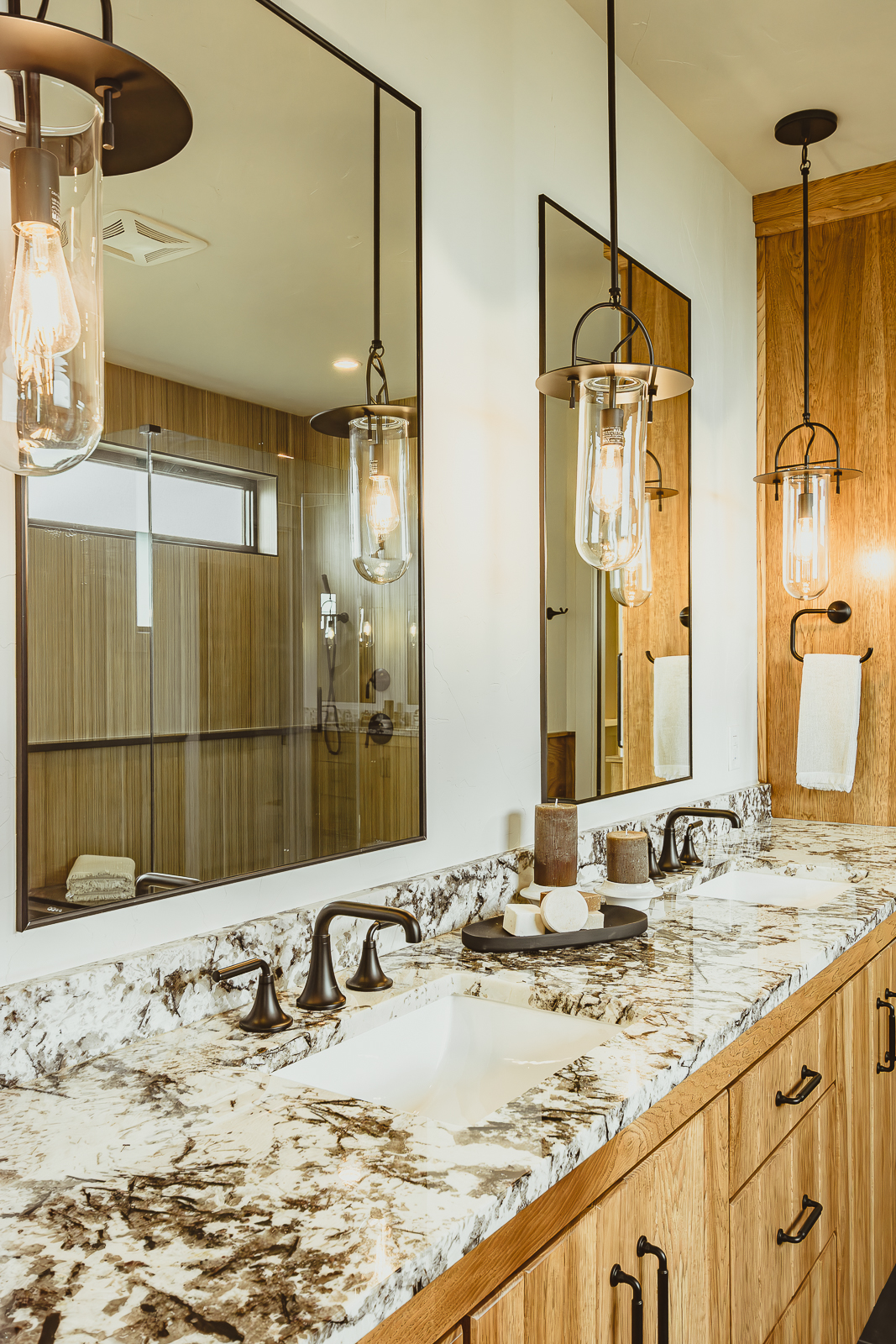 This gorgeous primary bath showcases three Edison bulb pendant lights suspended over a double vanity. This warm and inviting model home was showcased in the fall parade of homes
