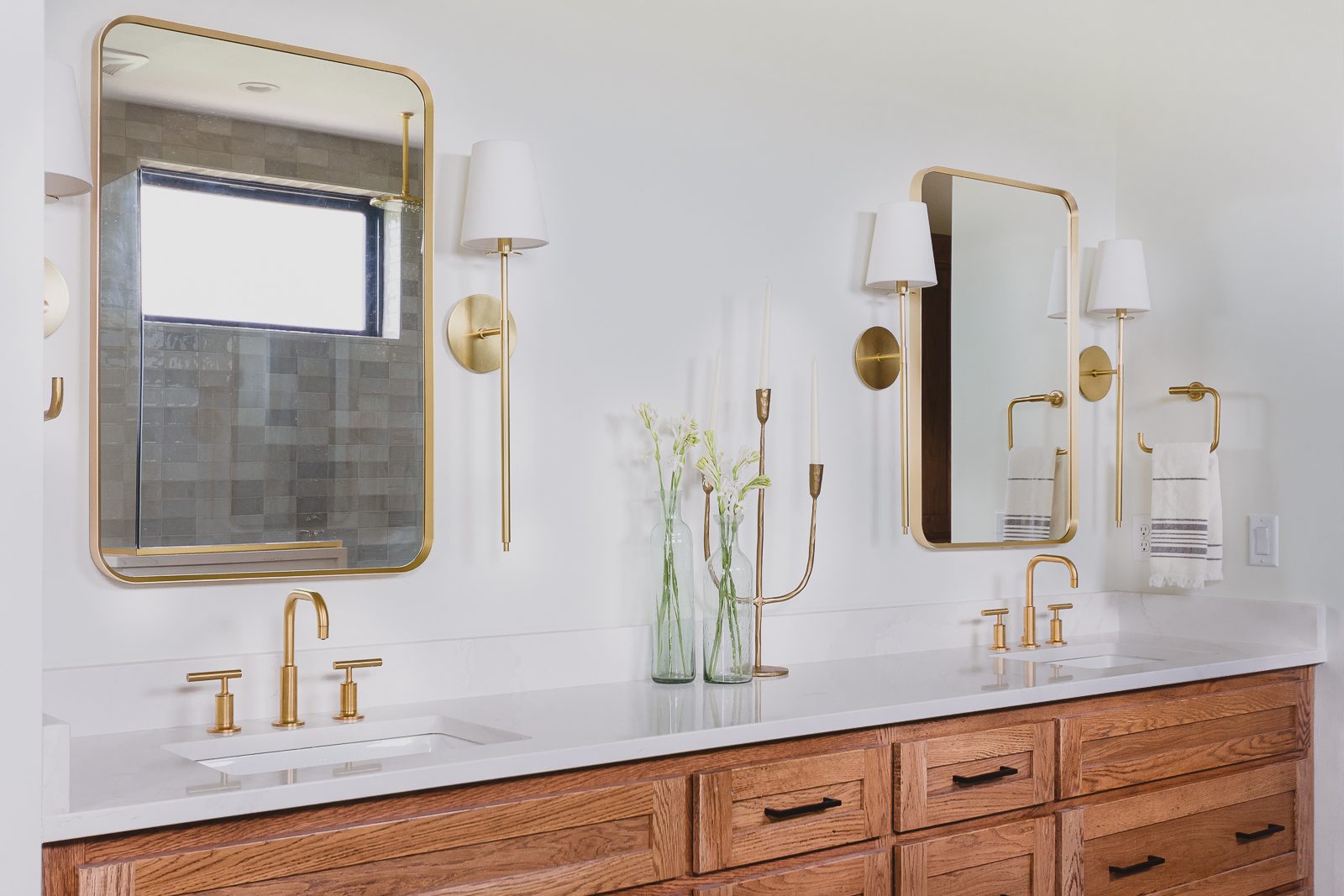 Primary bathroom shot with 2 sinks, brass plumbing hardware and simple lighting in the Haven - custom home project.