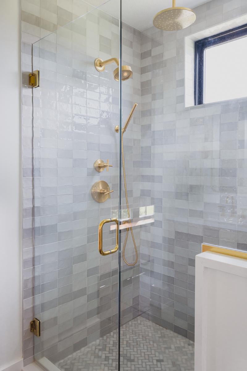 Tiled shower with brass plumbing fixtures in the Haven custom home project.