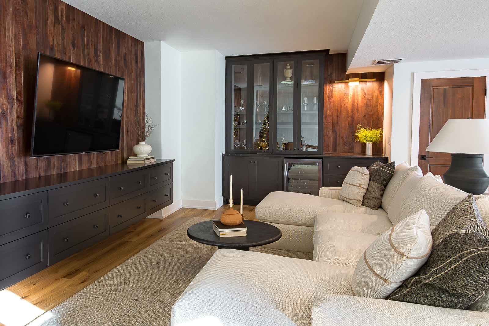 Lower level sectional facing a wall-mounted TV with ample custom storage and a built-in cabinet on the far wall in the Haven custom home project.