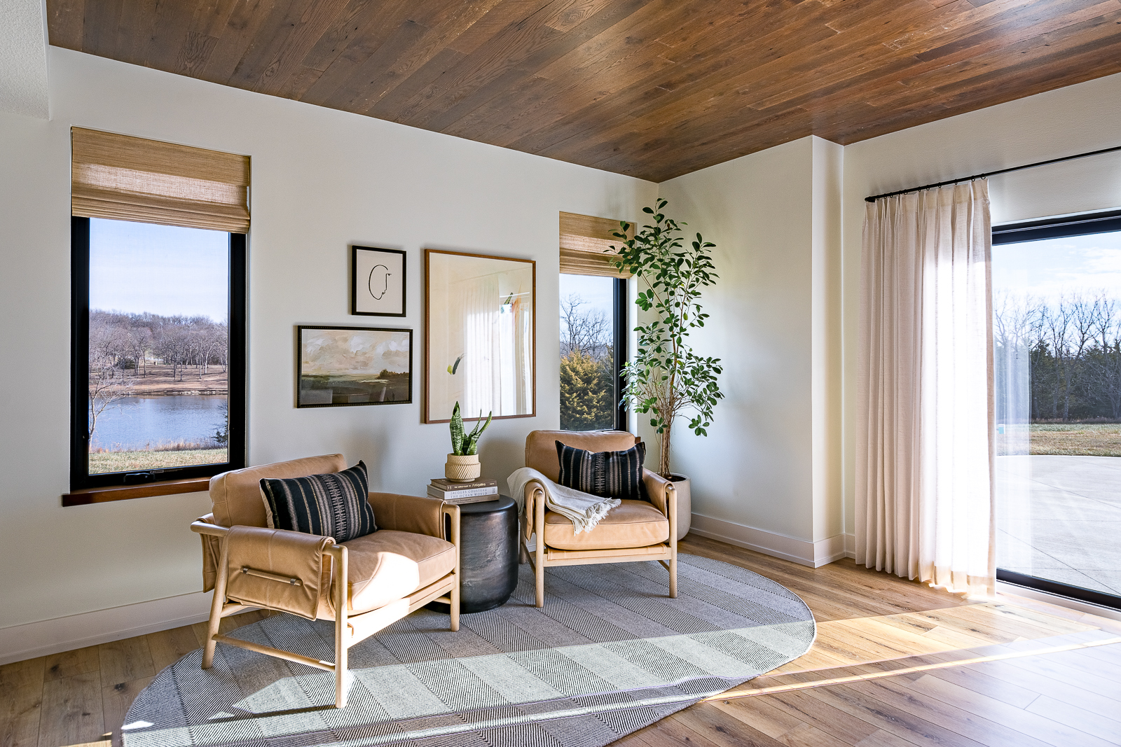 Lower level faux leather accent chairs in front of windows and a patio door overlooking a small pond at the Haven custom home project.