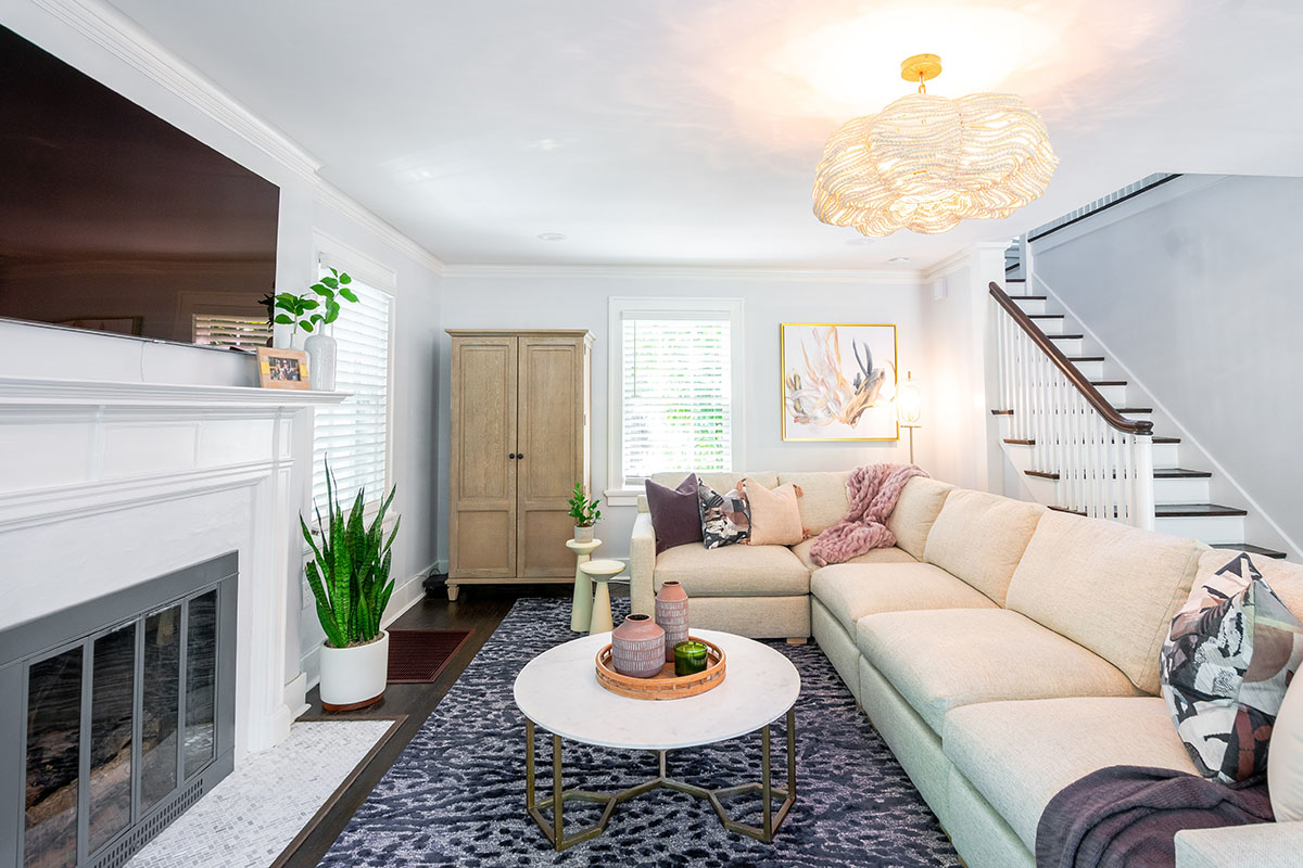 family room with a stone fireplace and cream colored sectional in a historic home renovation