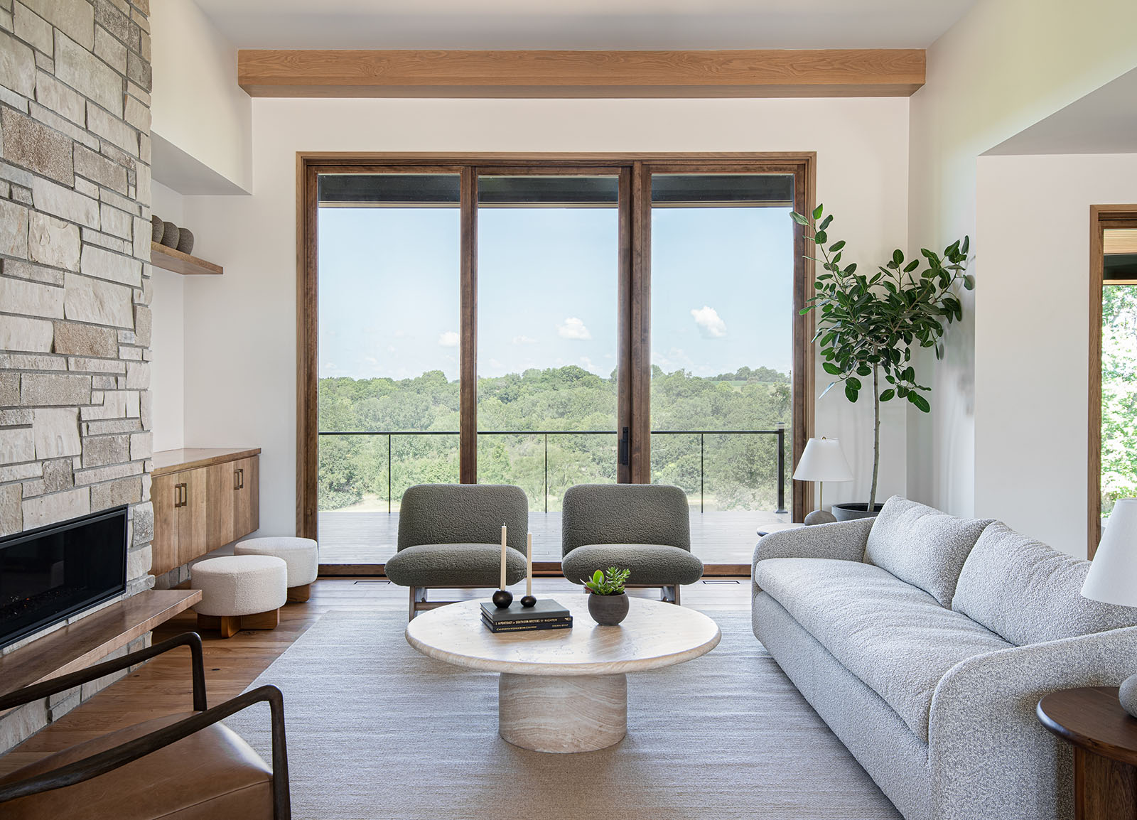 Featured on the interior design for homeowners page, this family room was showcased in the Holt, Missouri Artisan Home. Custom stone fireplace, engineered wood flooring, two accent chairs, and a plush boucle sofa.